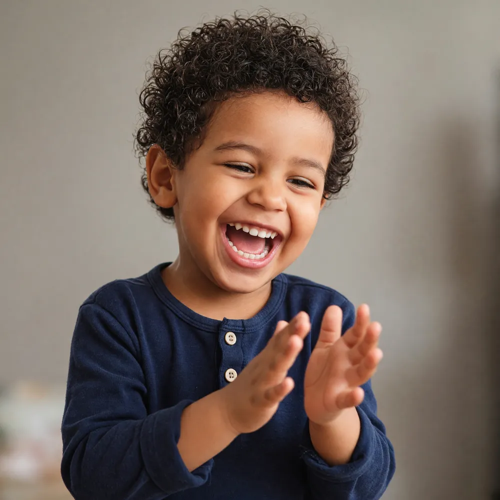 Jeune enfant riant et applaudissant pendant une séance d'activités inspirées Montessori à domicile, à Marrakech